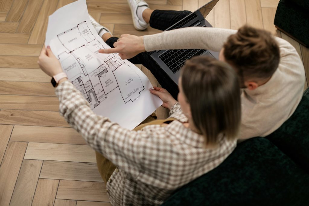 A couple examines a house blueprint together, exploring future home possibilities.